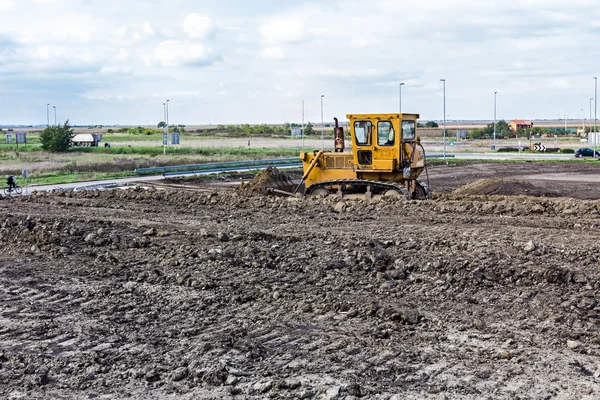 Bulldozer máquina está nivelando el sitio de construcción — Foto de Stock