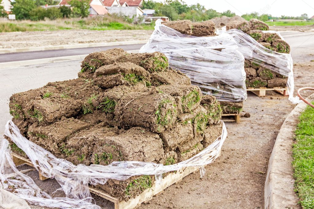 Pallet of sod rolls are wrapped in foil, unrolling grass