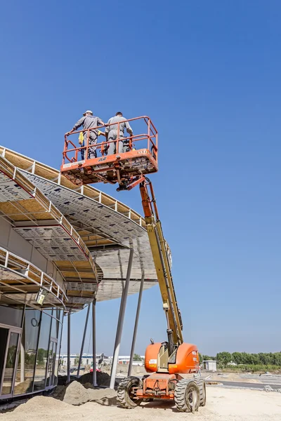 Los trabajadores de altura con la ayuda de un recolector de cerezas están trabajando en un nuevo encuentro — Foto de Stock