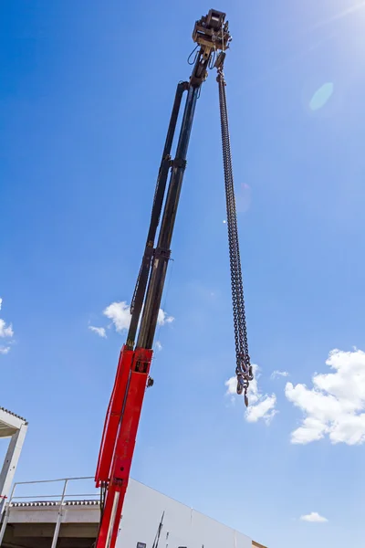 Grúa gancho con cadena está colgando por encima del sitio de construcción — Foto de Stock