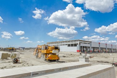 Sarı Mobil vinç inşaat sitesi üzerinden geçiyor.