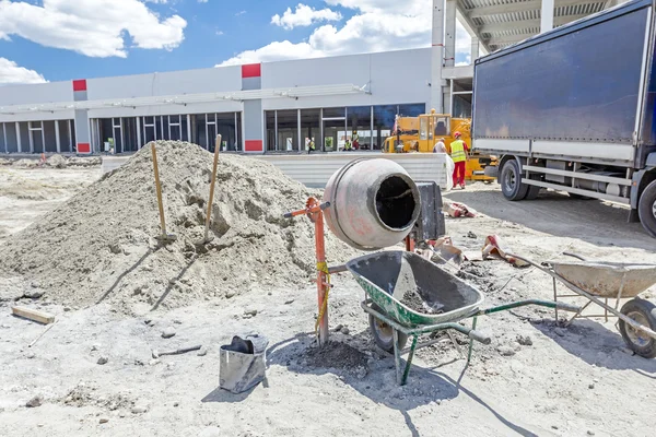 Máquina mezcladora de cemento y carretilla en el sitio de construcción — Foto de Stock