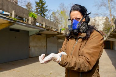 Yüzünde filtre maskesi olan kadın COVID-19 virüsüne karşı korunmak için ellerine lastik eldiven takıyor.. 