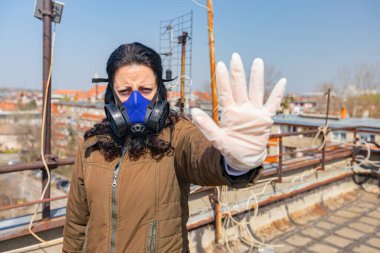 Medya baskısını durdurun. Endüstriyel maske takan kadının yüzünde kağıt filtre var. Elleri, hareketi, sosyal mesafesi, uzak durması, COVID-19 virüsüne karşı korunması, Corona.