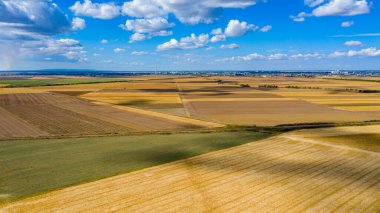 Tarım tarlalarının üzerinde, hasat mevsiminde ekilmiş araziler, beyaz kabarık bulutlu mavi gökyüzü onların gölgeleri yerde..