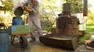 İnsan, elma dilimlerinden yapılmış kullanılmış meyve kesesini damıtma işleminden sonra küçük fıçıyı çöp olarak doldurmak için plastik kova kullanarak transfer ediyor.. 