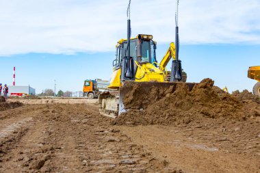 Buldozer zemini itiyor, düzleştiriyor, inşaat alanını eşitliyor.