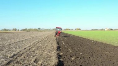 Düşük görüş açısı ile traktörün hareketli görüntüsü ekili tarım tarlasında toprağı sürerken, toprağı gelecek sezon yeni ekin için hazırlıyor..