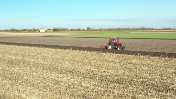耕作場に地面を耕しながらトラクターの上を後方に移動し 来年の新しい作物を植えるための土壌を準備する — ストック動画