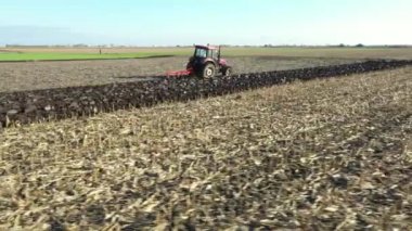 Düşük görüş açısı ile traktörün hareketli görüntüsü ekili tarım tarlasında toprağı sürerken, toprağı gelecek sezon yeni ekin için hazırlıyor..