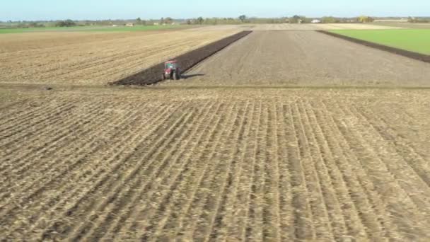 耕作地に地面を耕し 来年の新しい作物を植えるための土壌を準備するトラクターの軌道ドリー移動ショットと低ビュー — ストック動画