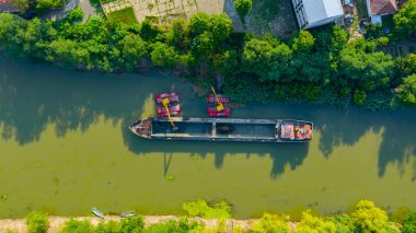 Nehir, kanal, derinleştirme ve kirli bir su yolundaki tortu, çamur, nehir yatağından kaldırma üzerine çalışan iki kazıcının üzerinde tepenin üstündeler..
