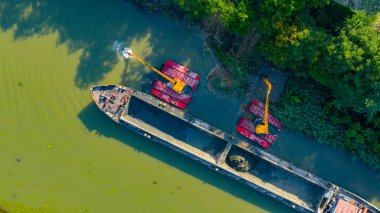 Nehir, kanal, derinleştirme ve kirli bir su yolundaki tortu, çamur, nehir yatağından kaldırma üzerine çalışan iki kazıcının üzerinde tepenin üstündeler..
