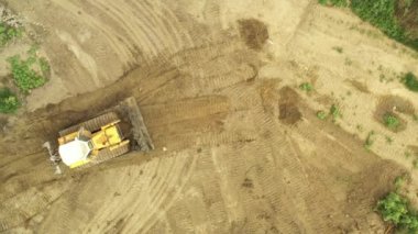Üst manzaralı buldozer çamurlu zemini itiyor, tortuyu düzleştiriyor, tortuyu eşitliyor.