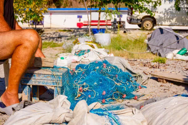 Bir Balıkçı Sahilde Bir Sandalyede Oturur Deniz Kabuklarından Balık Ağını — Stok fotoğraf