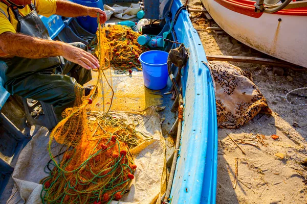 穿着橡胶长裤和靴子的渔夫正坐在他的船上 把鱼网堆积起来 准备在公海上钓鱼 — 图库照片