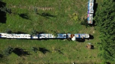 Yukarıdan bakıldığında, arı yetiştiricisi çizgi halinde, ahşap renkli arı kovanlarında, sıra sıra dizilmiş arı kolonilerinde durumu kontrol ediyor.. 