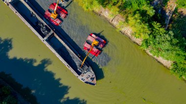 Nehir, kanal, derinleştirme ve kirli bir su yolundaki tortu, çamur, nehir yatağından kaldırma üzerine çalışan iki kazıcının üzerinde tepenin üstündeler..