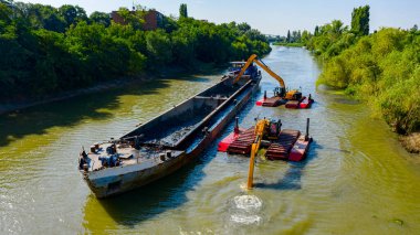 Nehir, kanal, derinleşen ve kirli bir su yolundaki tortu ve çamuru nehir yatağından kaldıran iki kazıcının üzerini tararken, tararken, tararken, tararken, tararken ve temizlerken.