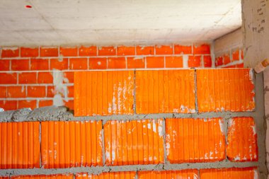 Mason, tuğla ustası düz olması için tel hattının yanına duvar örüyor..