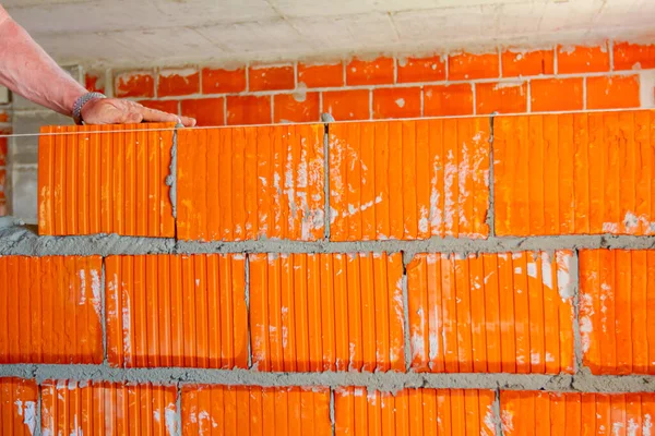 メイソンレンガ職人は赤いブロックを使って文字列ラインの横に壁を取り付けます — ストック写真