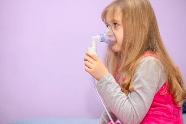 Astım sorunu olan bir çocuk yüzünde maskeyle solunum yapar..