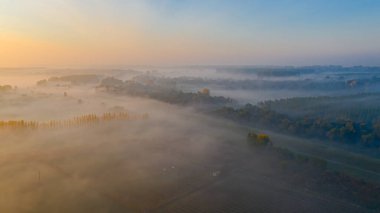 Sabahın erken saatlerindeki sislerin havadan görünüşü, yavaşça süzülen buhar, şafak vakti ekilmiş bitki örtüsünün üzerinde buhar..