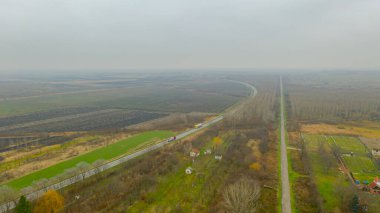 Toprak örtüsü ve asfalt yolu üzerinde etkin ve küçük yerleşim yerlerine yakın trafiği olan orman ağaçları arasında uzanır.. 