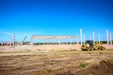 Santral sarı çizgili araç kullanıyor. İnşaat alanındaki zemini düzleştiriyor..