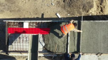 Üst manzarada, inşaat işçilerinin genel giderleri, mikser kamyonundan dökülen metalle yeni betonu kareye sabitliyor..