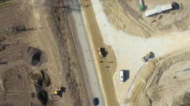 Dolly yukarı doğru hareket ediyor, üst görünümün üzerinde, üzerinde sivri uçlu dev yol silindiri sıkıştırıcı toprak, etkin trafiğin yanındaki yol temeli için inşaat sahasında kum var..