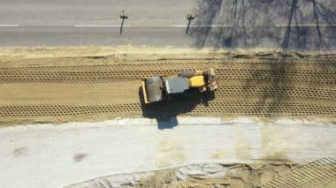Üst manzaranın üstünde, devasa bir yol silindirinde sıkıştırıcı toprak olarak vibrasyon plaka sıkıştırıcısı, etkin trafiğin yanındaki yol temeli için inşaat alanında kum..