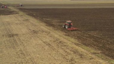 Üç traktörün hava üst görüntüsü, biri bir disk tırmığı sürüklüyor, diğeri tohum ekme makinesi çekiyor, üçüncüsü tarla, toprak, yeni buğday ekimi..
