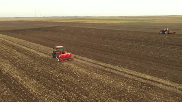 上部には 耕作可能なフィールド 新しい小麦作物を植える上に種子ドリルマシンを引っ張るトラクターのドリー移動ショット — ストック動画