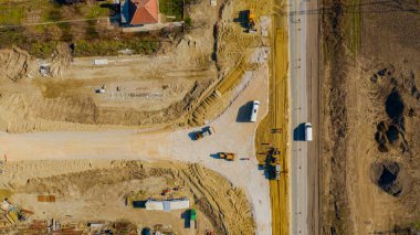 Üst görünümün üzerinde, bıçağın seviyelendirme makinesinin üzerinde, grader, yeni dairesel yol için kum tabakası düzleştiriyor, inşaat halindeki döner kavşak, etkin trafiğin yanındaki yol temeli.