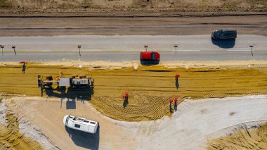 Üst görünümün üzerinde, bıçağın seviyelendirme makinesinin üzerinde, grader, yeni dairesel yol için kum tabakası düzleştiriyor, inşaat halindeki döner kavşak, etkin trafiğin yanındaki yol temeli.