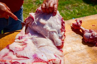 Kasap çiğ domuz etini küçük parçalara ayırıyor. Tahtadaki keskin bir bıçakla..