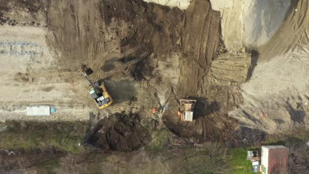 建物の敷地内の彼のバケツの中に地面を運ぶように車輪のある掘削機の上のビューの上に オーバーヘッドのドリー移動 どこに不足しているレベル 進行中のプロジェクトを広めるために — ストック動画