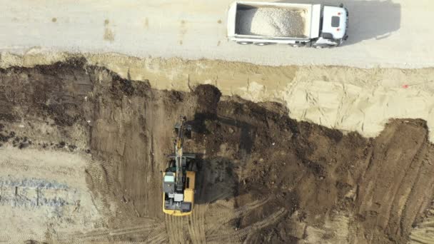 建物の敷地内の彼のバケツの中に地面を運ぶように車輪のある掘削機の上のビューの上に オーバーヘッドのドリー移動 どこに不足しているレベル 進行中のプロジェクトを広めるために — ストック動画