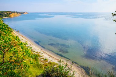 Çimenlerle ve ağaçlarla kaplanmış uçurum deniz kıyısının üzerindedir. Uzakta yerleşim 