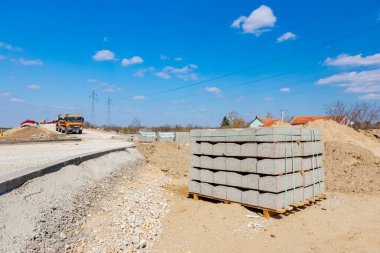 İnşaat alanındaki ahşap palette asfalt yol için paketlenmiş sınır taşları yığını.