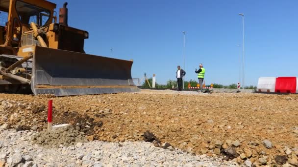 推進中の2つのブルドーザーの低角度ビュー 建物現場での新しい道路基盤のための砂利のレベリング 土工作物の機械化 — ストック動画