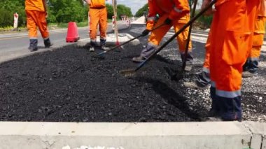 Çok az işçi tırmığı düzleştirmek için kullanıyor, doğru ölçümlere taze asfalt katmanı yerleştiriyor, sıcak asfalt döküyor..