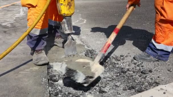 建筑工人用气动钻砸碎沥青 男人用铲子捡起并扔掉破碎的零件 — 图库视频影像