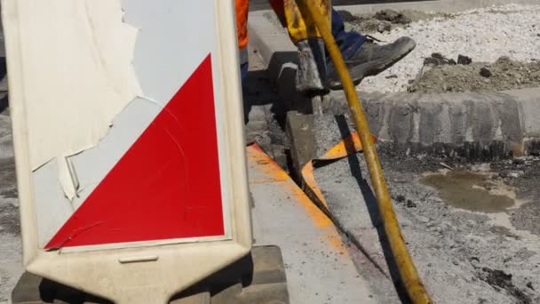 建設労働者は 空気圧ジャックハンマーでアスファルトを破壊します ショベルを使って割れた部品を拾って捨てる男 — ストック動画