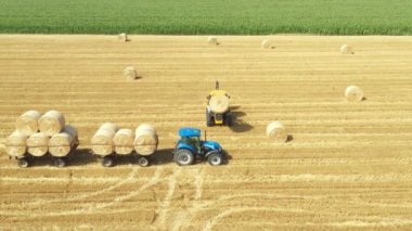 Kazıcının üstünde, karavana saman balyaları yüklerken, tarla arazisinde traktörle çekilirken, forklift bıçağı ve ek taşıyıcı kullanarak,.