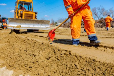 İnşaat alanındaki yol temeli için kumu düzleştiren buldozer ve kazıcıya bak, mekanizasyon.