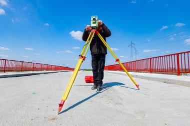 Mühendis inşaat halindeki köprüyü ölçüyor. Anketçiler büyük inşaat projelerine girişmeden önce kesin ölçümler yapıyorlar.