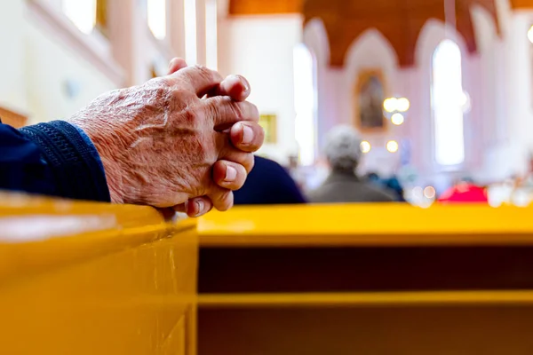 Prayer\'s hands as they are praying with their priest at Sunday morning in old and small Catholic Church.