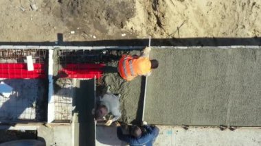 Üst manzarada, inşaat işçilerinin genel giderleri, mikser kamyonundan dökülen metalle yeni betonu kareye sabitliyor..